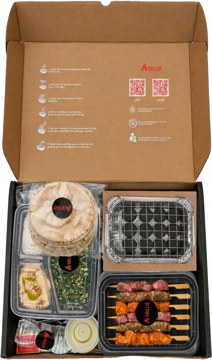 An open Grillie BBQ box with skewers, charcoal, sauces and bread